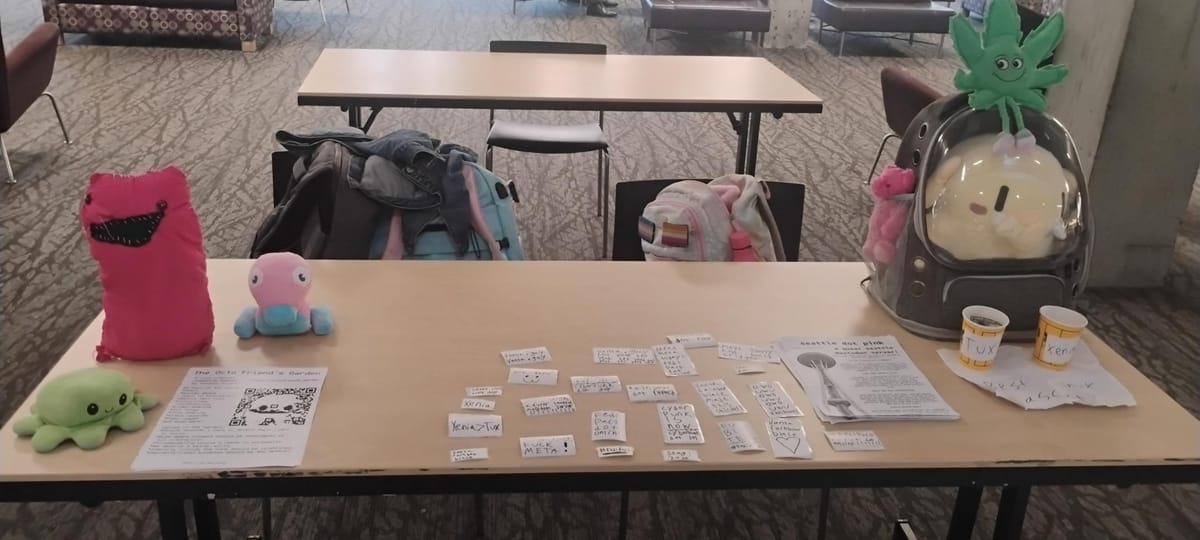 table with a buncha stickers and flyers and plushies on it